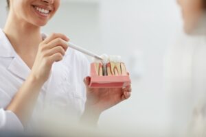 Imagen dentista con molde de dientes en las manos enseñando a un paciente, alternativa.